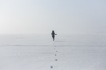 A woman runs on a snowy field. - Powered by Adobe
