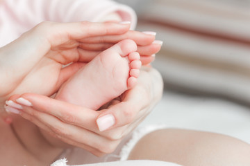 Baby`s feet closeup picture. Mother`s hands holding child`s foot. Little girl`s fingers at front. Background of parenthood.