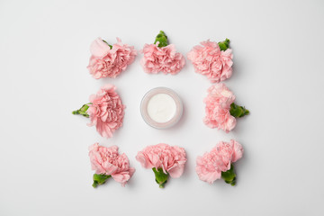 Obraz na płótnie Canvas Flat lay of carnations flowers in square arranging and cream container on white background