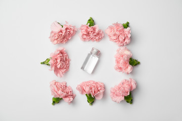 Flat lay of carnations flowers in square arranging and cosmetic bottle on white background