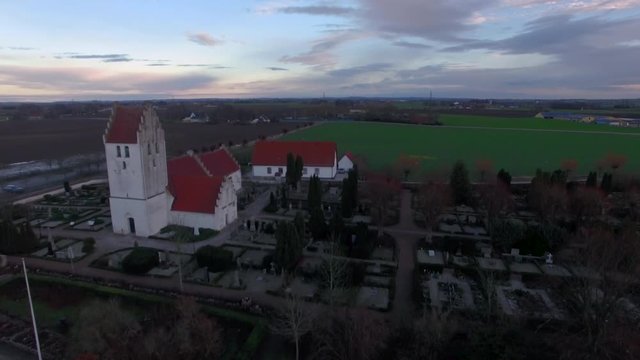 Aerial footage when flying over and mediaeval church and open fields in Sweden.