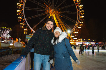 Happy cheerful young couple having fun at the ice skating park