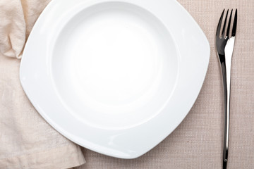 Empty white plate. On delicate beige tablecloth. Concept to include your food and your text.