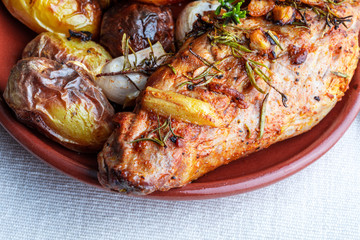 Delicious and appetizing roasted pork tenderloin with spices and potatoes (black pepper, olive oil, garlic, fresh rosemary, salt). Top view.