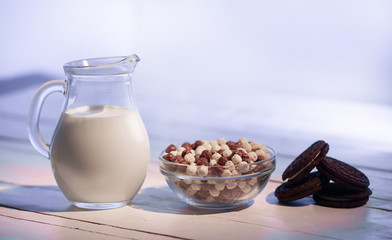 Fast healthy breakfast. Chocolate balls, milk in a jug a wooden background