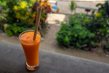 Yellow mango smoothie on tropic resort balcony. Orange fruit shake closeup photo. Refreshing fruit drink.
