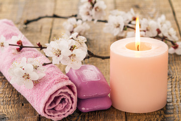 Obraz na płótnie Canvas Soap with towel for bathroom procedures and burning candle with flowering branch of apricot tree