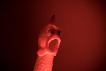A Plastic Toy Chicken with surprised face in red light