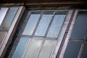 A horror scene of damaged, old, scary and abandoned airplane shed, hangar, factory. Darkness, shadows, broken glass and cracks in windows are causing goosebumps and fear. Life threatening building