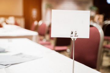 Mock up white Label for blank menu frame in seminar room or conference hall light on desk groups for letter, Event Background. Business Talk Presentation.