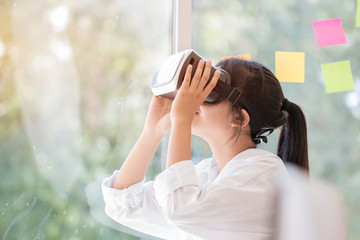 Virtual reality interaction headset by Asian Beautiful young female wearing touching air during VR box for playing game simulator future media. Technology digital Futuristic innovation device concept