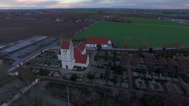 Aerial footage when flying over and mediaeval church and open fields in Sweden.