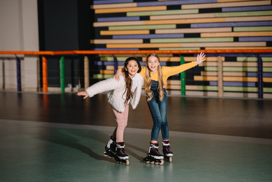 Happy smiling children skating together with raised hands