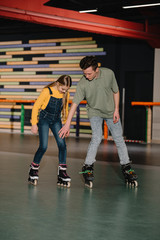 Obraz premium Handsome young instructor showing skating technics to attentive child
