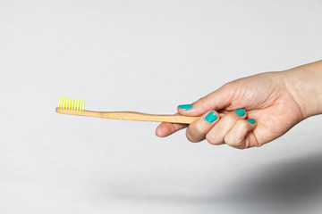 Bamboo Toothbrush in a hand isolated on grey