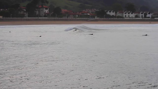 Alumnos de escuela de surf haciendo pr&aacute;cticas en las olas que llegan a la costa