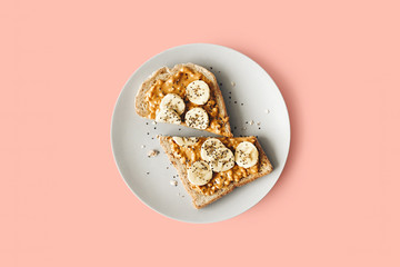 Peanut butter chia seed banana toast for breakfast on a pink background, healthy snack, top view