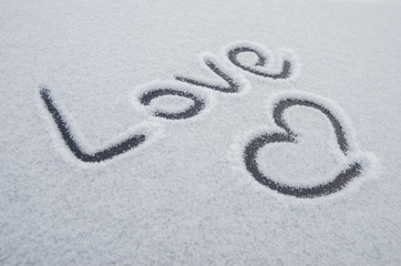 Writing text LOVE on the snow, painted heart on snow
