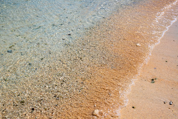 Fototapeta na wymiar Turquoise sea water on sandy beach. Sea tide on sand. Tropical seaside photo. Marine holiday. Seashore landscape