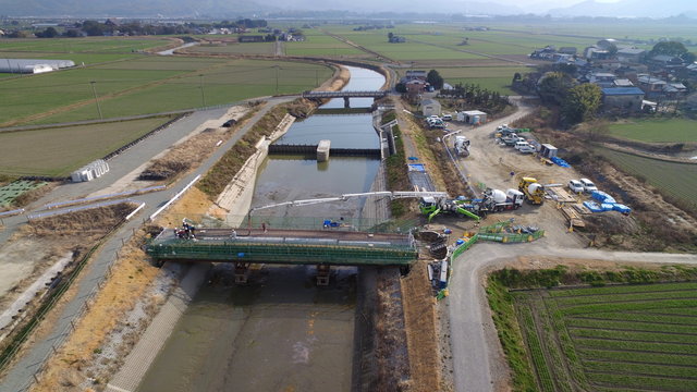 水害対策の河川拡張による橋の架け替え工事、鉄筋間へのコンクリート打ち込み工事の様子、