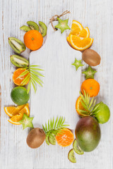 Green palm leaves and fresh tropical slices of fruits