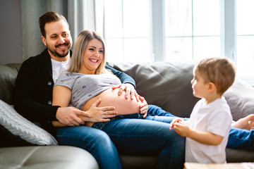 A Beautiful pregnant mother and father with her children at the living room