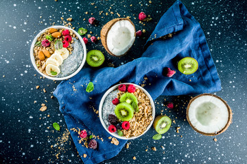Fototapeta na wymiar Homemade granola with chia seeds yogurt pudding, fresh fruit and berries, on dark blue concrete background copy space