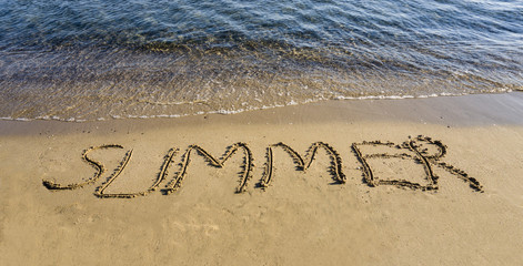 Summer word written / handwritten in sand on wet sandy beach. New summer is coming and holiday vacation travel time concept. I love summer and need holiday message on coast. Copy space for ad banner.