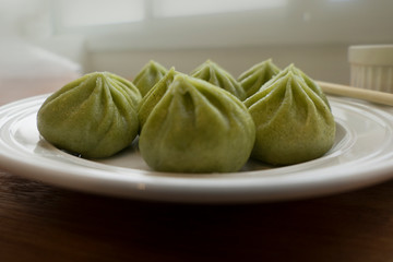 a plate of multiple green Dim Sum dumplings