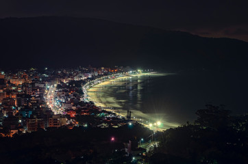 Naklejka na ściany i meble Panoramic view of Bombinhas city and Praia de Bombas at night. Touristic season, city buildings, main avenue Leopoldo Zarling and Bombas beach.