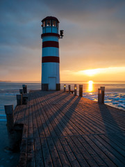 Lighthouse at jetty on the lake in winter