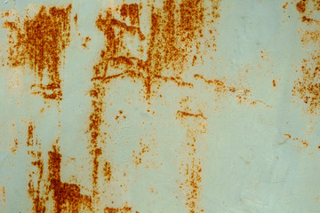 Abstract shapes of rust streaks on a painted metal outbuilding door