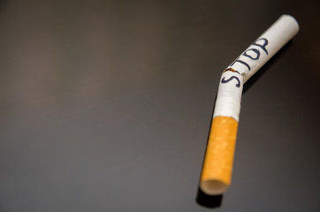 broken cigarette with the word stop on a dark background; stop smoking concept, close upм