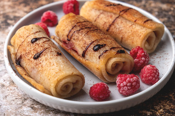 Delicious homemade crepes with raspberries and chocolate syrup, copy space