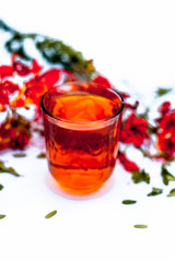 Close up shot of herbal organic fresh extract of peacock flowers in a transparent  glass  with flowers isolated on white.