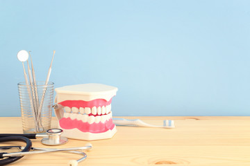 Dental care tools use for dentist and plastic teeth model in the clinic. Wooden blue background.