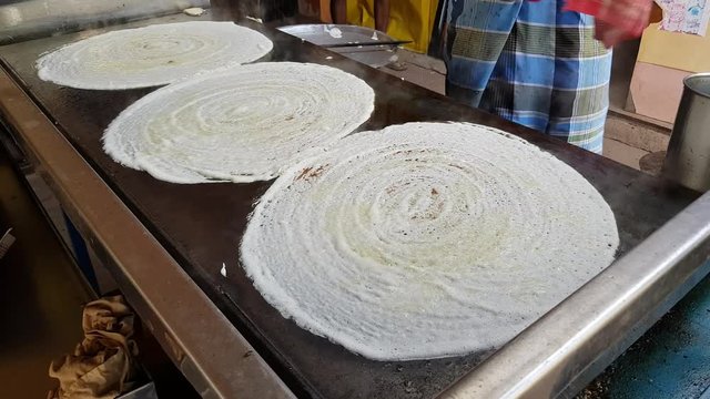 A man making dosa on a huge stone plate