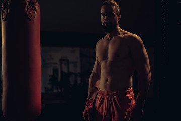 Fototapeta premium Bearded fighter standing by the heavy bag