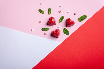 Greeting card with Valentine's Day. Handmade chocolate sweets pastry with strawberry filling, on a tap, rose and white background. Top view, copy space