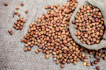 Close up shot of chickpea or chana or gram or Cicer arietinum in a gunny bag on a brown colored background.