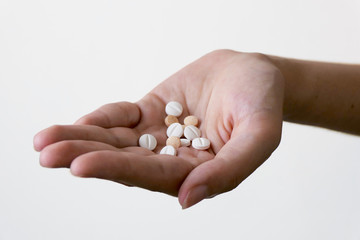 Hand holding various Medicine Pills on a white background