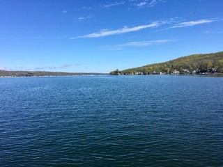 The clear, still water of Canadice Lake, one of Finger Lakes in New York, in horizontal orientation in Autumn, with a blue sky background 