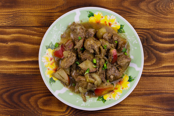 Stewed chicken liver with apple and onion on wooden table
