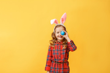 Cheerful little kid girl with bunny ears with an easter egg on a colored background.