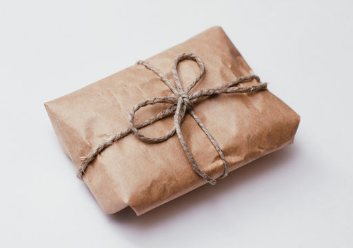 Box parcel wrapped in brown craft paper tied hemp cord on white background. 