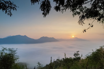 sunrise at Phu Thok, beautiful mountain view misty morning of top mountain around with sea of mist with colorful yellow sun light in the sky background, Chiang Khan District, Loei, Thailand.