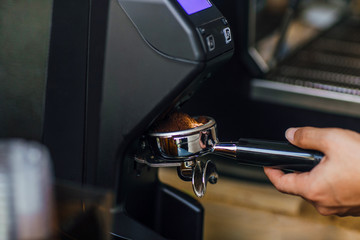 Morning coffee, Professional barista grinding coffee into portafilter to make espresso hot drink. Focus selection