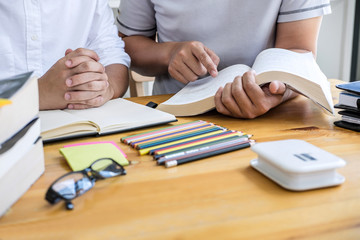 Education, teaching, learning concept. High school students or classmates group tutor in library studying and reading with helps friend doing homework and lesson practice preparing exam to entrance