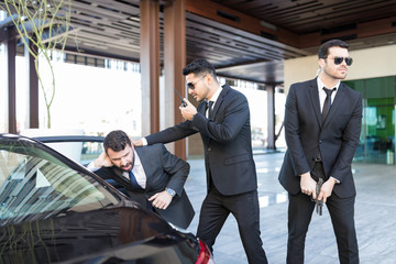 Hispanic Boss Getting In Car With Help Of Bodyguards