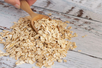 Dried oats or oatmeal in spoon on the wood table. Its are a nutrient-rich food associated with protein and fiber.